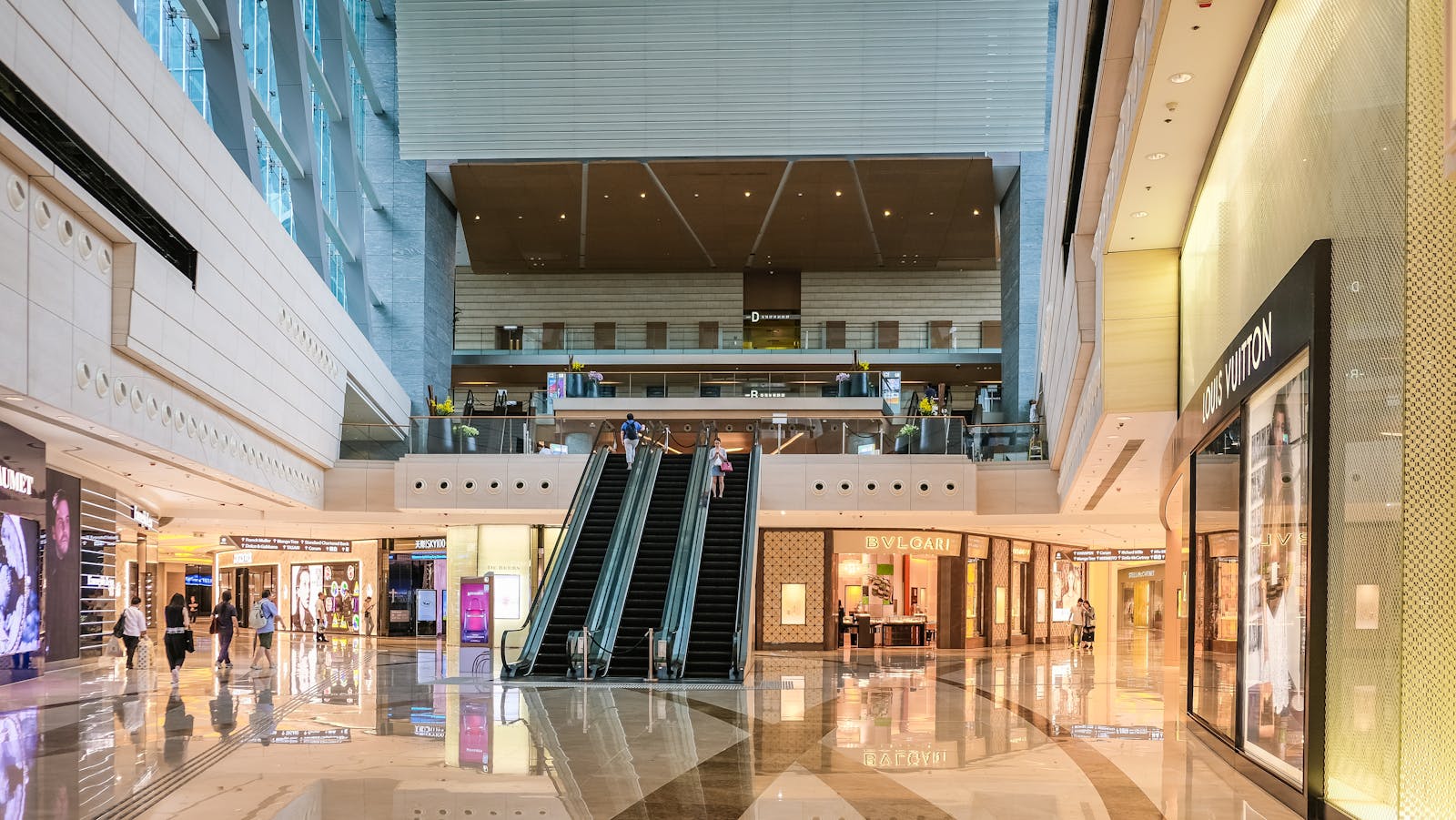 Modern shopping mall interior with escalators and luxury stores in Hong Kong.